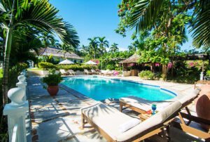 swiming pool and beach chairs with surrounding garden and some small villas