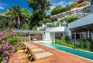 Swimming pool and beach chairs in tropical setting villa backyard