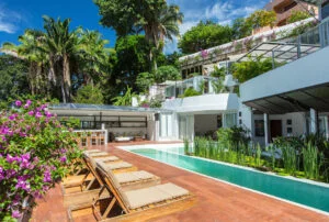 Swimming pool and beach chairs in tropical setting villa backyard